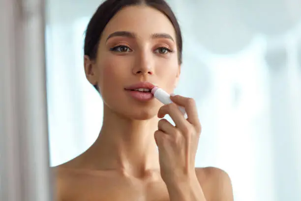Lips Protection. Beautiful Woman With Beauty Face, Full Lips Applying Lip Balm, Lipcare Stick On. Portrait Of Female Model With Natural Makeup. Lips Skin Care Cosmetics Concept. High Resolution