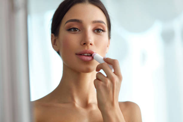 beautiful woman with beauty face applies balm on lips. skin care - lipstick imagens e fotografias de stock