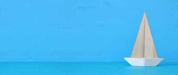 istock nautical concept with white decorative sail boat over blue wooden table and background. 943062488