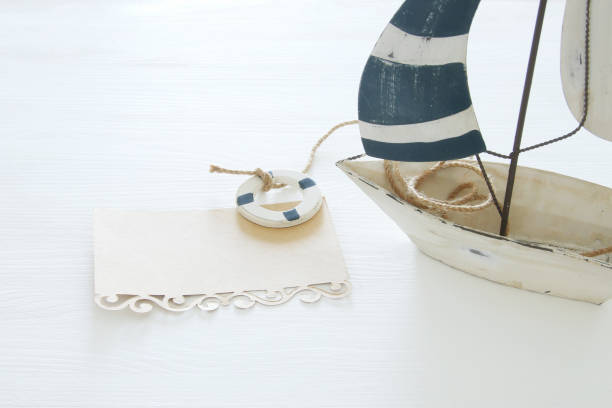 istock nautical concept image with white decorative sail boat and note over white wooden table. 943062896