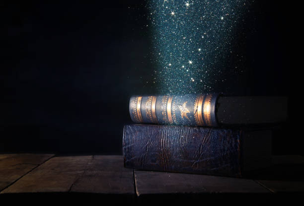 image of stack of antique books over wooden table and dark background
