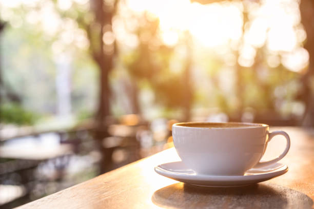 istock White coffee cup on wooden table or counter in coffee shop and blur light bokeh background 943067310