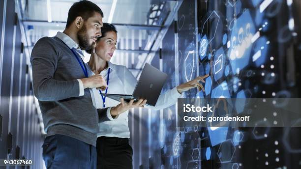 Male It Specialist Holds Laptop And Discusses Work With Female Server Technician Theyre Standing In Data Center Rack Server Cabinet With Cloud Server Icon And Visualization Stock Photo - Download Image Now