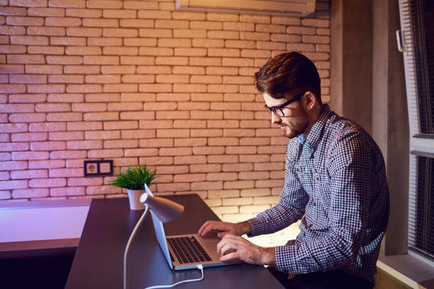 istock A man bearded freelancer with a laptop works in the evening 943073618