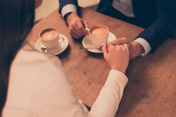 istock A couple sitting in a cafe with coffee holding hands 943092430