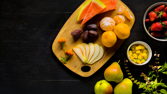 Dark wood and lighting concept of healthy vegan eating. Variety of fruit