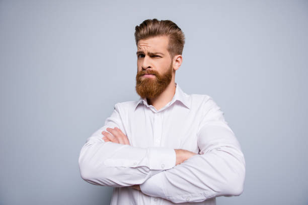 Portrait of serious confident bearded man keeping  crossed hands and expressing distrust emotion
