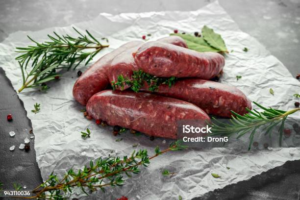 Photo libre de droit de Fraîchement Préparés Cru Race Bouchers Saucisses En Peaux Aux Herbes Sur Papier Froissé banque d'images et plus d'images libres de droit de Saucisse