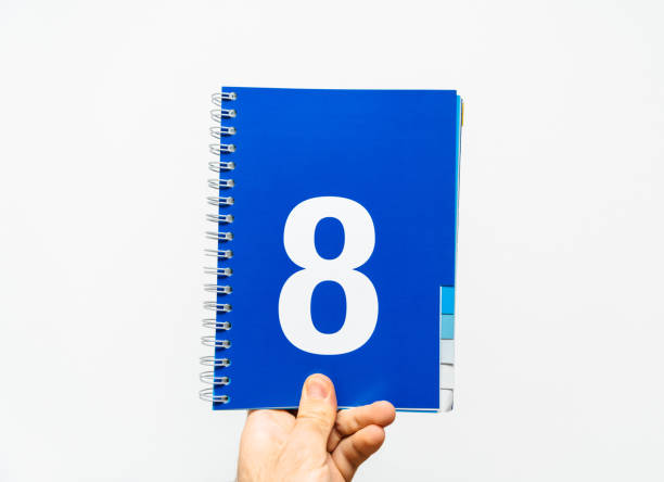 istock Male hand holding notebook with big number 8 on blue color, 943114552