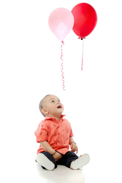 Boy inflating green balloon on orange background, space for text