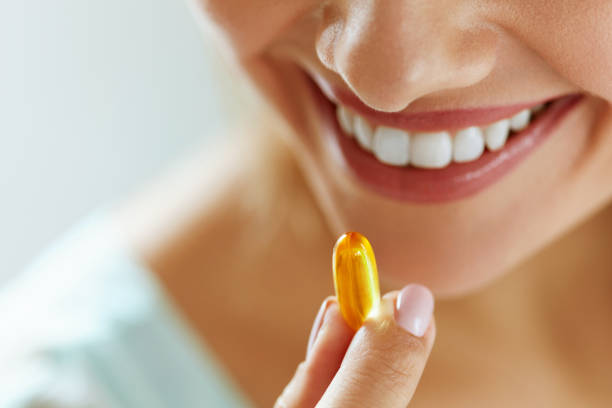 z bliska pięknej kobiety biorąc kapsułki oleju rybnego w ustach - nutritional supplement pill eating food zdjęcia i obrazy z banku zdjęć