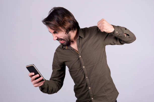 istock Young afro-haired grimaces at cellphone he holds 943123112