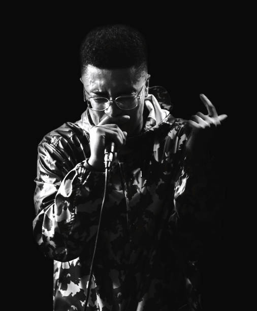 Black male rapping with microphone in camo jacket and glasses. stock photo