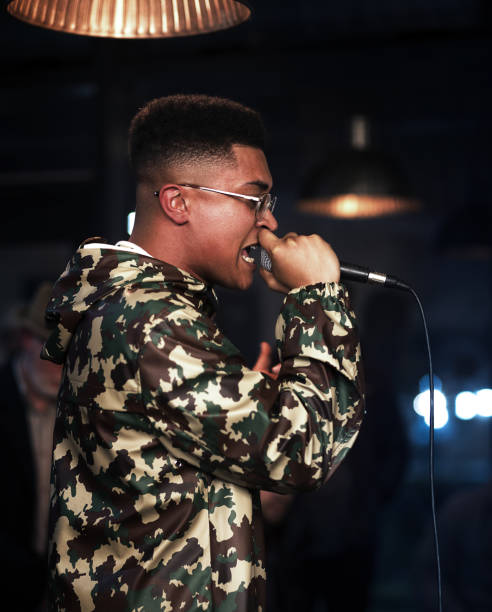 Black male rapping with microphone in camo jacket and glasses. stock photo