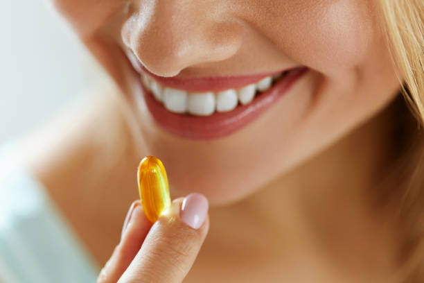 美しい女性の口の中に魚油カプセルを取るをクローズ アップ - nutritional supplement pill eating food ストックフォトと画像