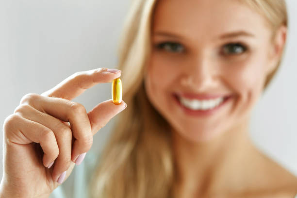 witamina i suplement. piękna kobieta trzymająca kapsułę z olejem rybnym - nutritional supplement pill eating food zdjęcia i obrazy z banku zdjęć
