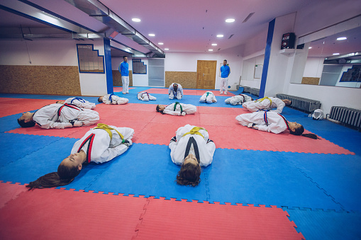 Group of people, taekwondo kids team stretching on the floor all together, before training.