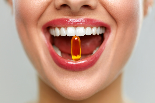 Boca de la hermosa mujer con la píldora en los dientes. Chica tomando vitaminas photo