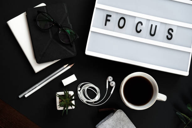 istock Motivation office table desk. Workspace with diary, plant, headphones, coffee, pencils, table with the word focus. Flat lay, top view