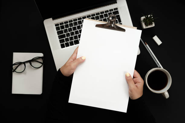 istock Home office workspace mockup in woman hands with laptop, coffee, notebook and accessories. Flat lay, top view 943135978
