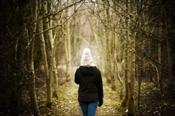 Girl wrapped up warm about to enter into a mysterious wood. stock photo