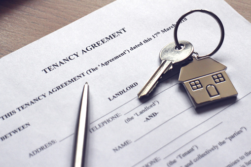 A house key resting on a tenancy agreement contract.