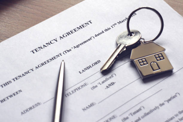 Tenancy Agreement A house key resting on a tenancy agreement contract. tenant stock pictures, royalty-free photos & images