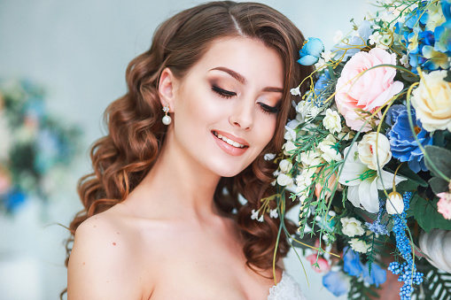 Beautiful young bride with wedding makeup and hairstyle indoor .Closeup portrait of young gorgeous bride in studio . Weddong