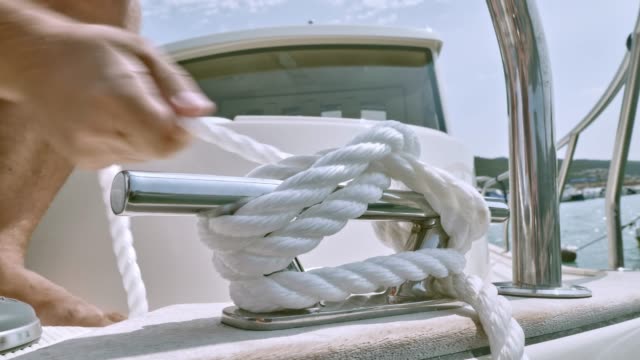 Male hands tying a knot to the cleat on the boat