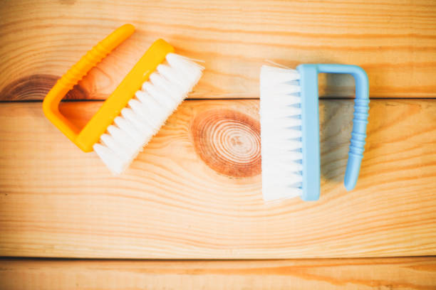 Cleaning house or office concept. Blue and yellow plastic brushes on natural wooden background, close up, top view