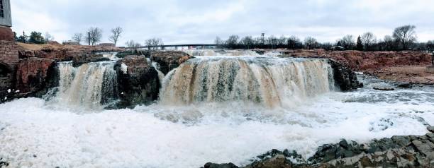 la big sioux rivière coule sur les rochers dans le dakota du sud de sioux falls, avec vue sur la faune, les ruines, les chemins du parc, train voie pont, arbres et ville dans les environs et arrière-plan - big sioux river photos et images de collection