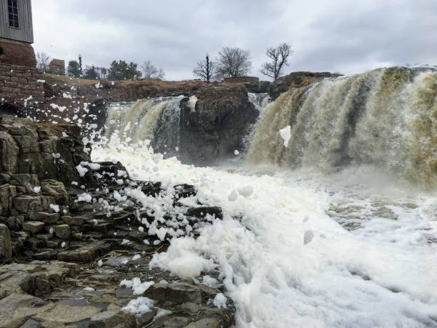 la big sioux rivière coule sur les rochers dans le dakota du sud de sioux falls, avec vue sur la faune, les ruines, les chemins du parc, train voie pont, arbres et ville dans les environs et arrière-plan - big sioux river photos et images de collection