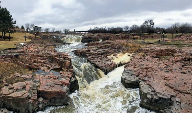 la big sioux rivière coule sur les rochers dans le dakota du sud de sioux falls, avec vue sur la faune, les ruines, les chemins du parc, train voie pont, arbres et ville dans les environs et arrière-plan - big sioux river photos et images de collection