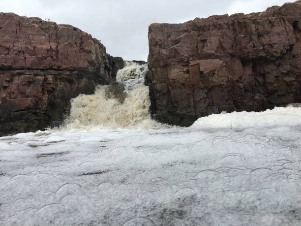 la big sioux rivière coule sur les rochers dans le dakota du sud de sioux falls, avec vue sur la faune, les ruines, les chemins du parc, train voie pont, arbres et ville dans les environs et arrière-plan - big sioux river photos et images de collection