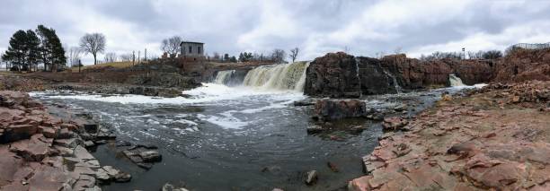 la big sioux rivière coule sur les rochers dans le dakota du sud de sioux falls, avec vue sur la faune, les ruines, les chemins du parc, train voie pont, arbres et ville dans les environs et arrière-plan - big sioux river photos et images de collection