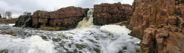 la big sioux rivière coule sur les rochers dans le dakota du sud de sioux falls, avec vue sur la faune, les ruines, les chemins du parc, train voie pont, arbres et ville dans les environs et arrière-plan - big sioux river photos et images de collection