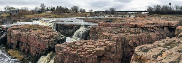 la big sioux rivière coule sur les rochers dans le dakota du sud de sioux falls, avec vue sur la faune, les ruines, les chemins du parc, train voie pont, arbres et ville dans les environs et arrière-plan - big sioux river photos et images de collection