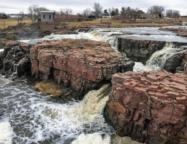 la big sioux rivière coule sur les rochers dans le dakota du sud de sioux falls, avec vue sur la faune, les ruines, les chemins du parc, train voie pont, arbres et ville dans les environs et arrière-plan - big sioux river photos et images de collection