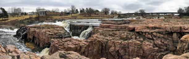 la big sioux rivière coule sur les rochers dans le dakota du sud de sioux falls, avec vue sur la faune, les ruines, les chemins du parc, train voie pont, arbres et ville dans les environs et arrière-plan - big sioux river photos et images de collection