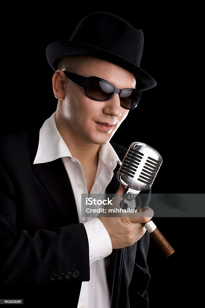 Singer with old-fashioned microphone Singer with old-fashioned microphone and black hat Adult Stock Photo