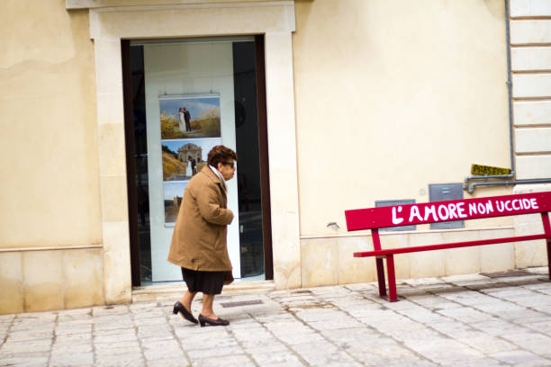 scicli, sicilia: mujer senior pasar banco rojo - scicli fotografías e imágenes de stock