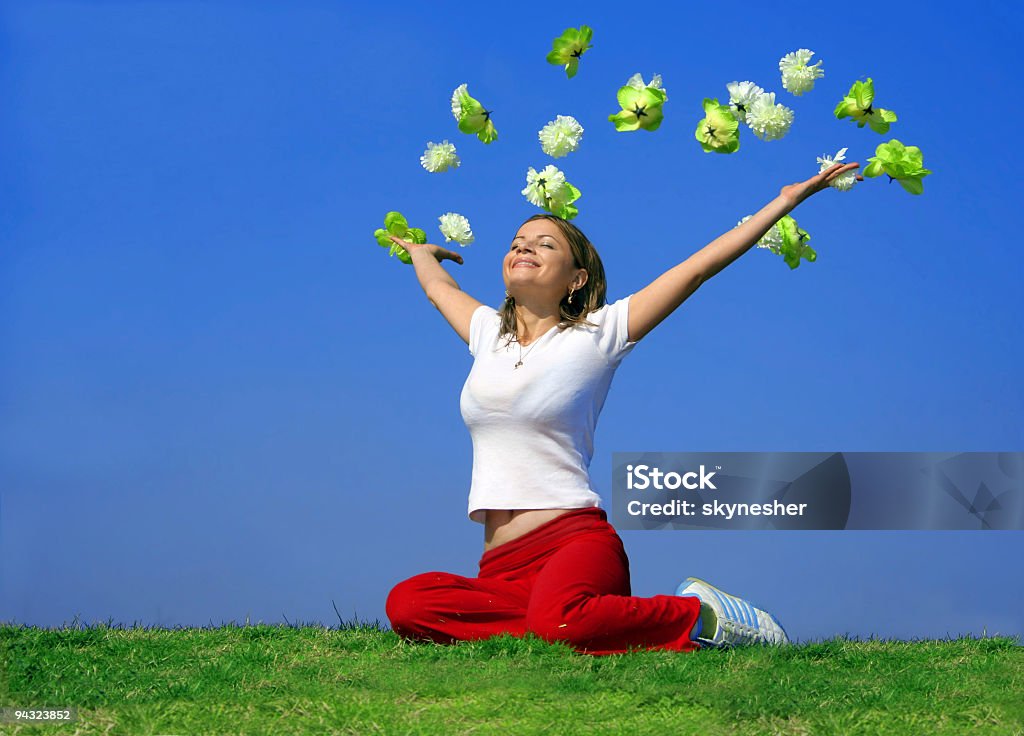 Felice giovane donna con fiori all'aperto volante - Foto stock royalty-free di Fiore