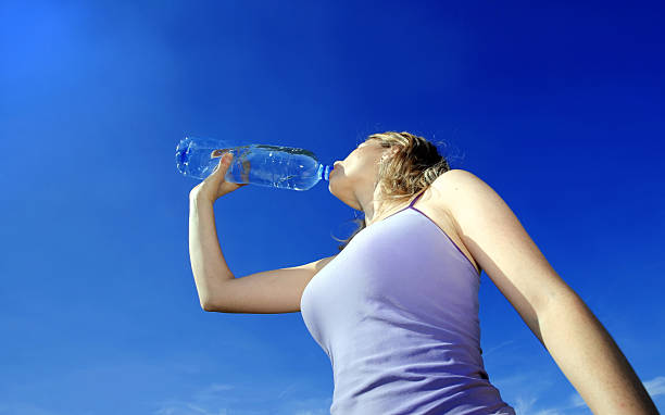 mädchen trinkwasser gegen den blauen himmel - exercising sensuality water bottle relaxation exercise stock-fotos und bilder