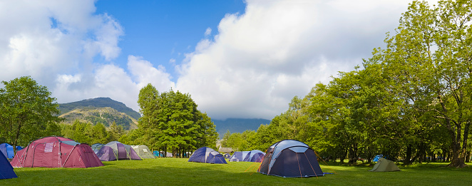 Modern dome tents pitched on a picturesque campsite surround by mountains and forests. Adobe RGB 1998 color profile.