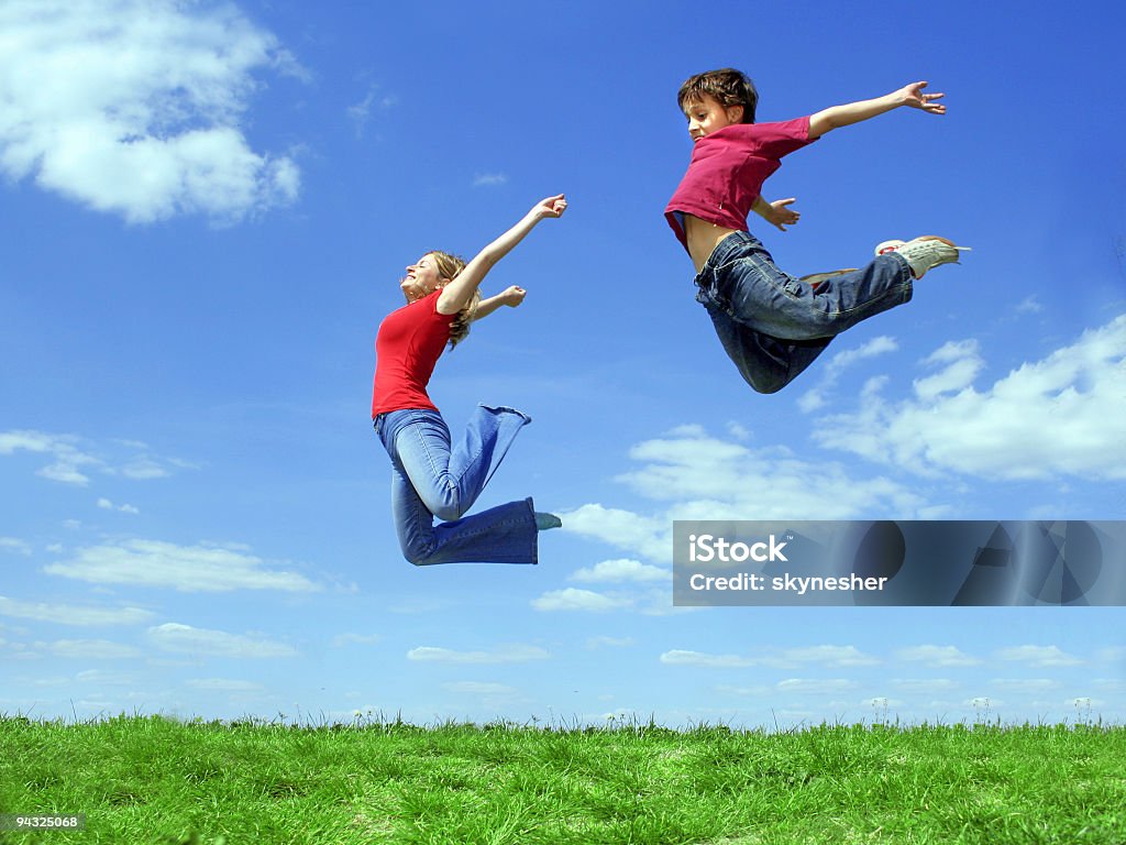 Girl and child jumping on meadow  Adult Stock Photo