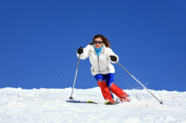 Skiing woman on ski piste with cable car in the background