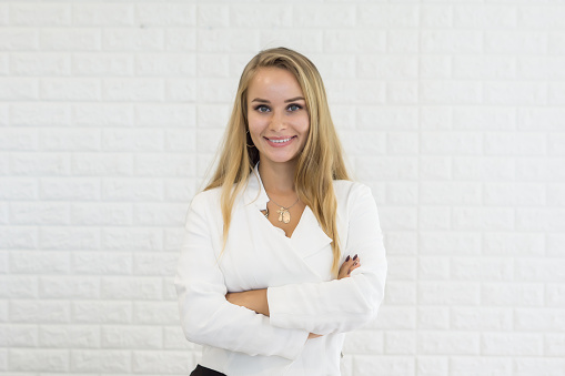 Young business woman standing against brick wall in the office with copy space