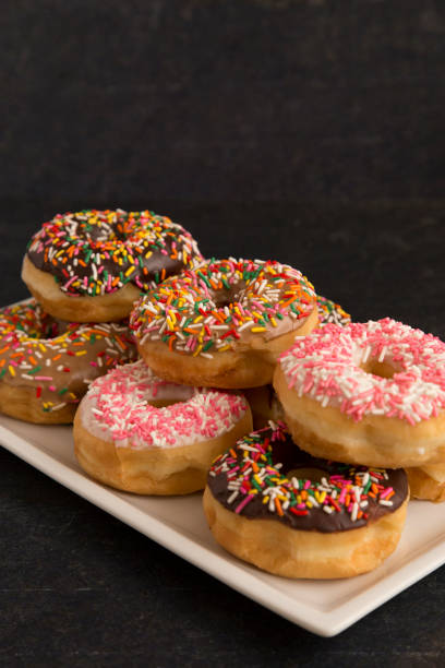 istock Various Flavors of Sprinkle Donuts on a Slate Counter 943288710