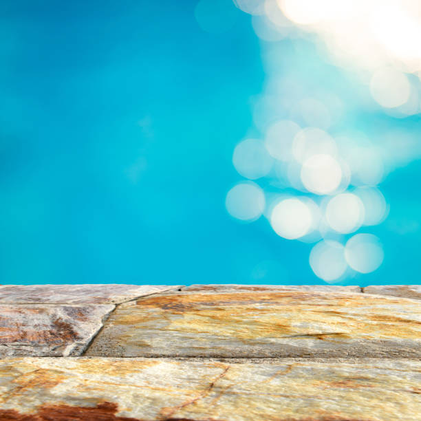 istock Brown stone table top and blurry blue water bokeh abstract background 943289808