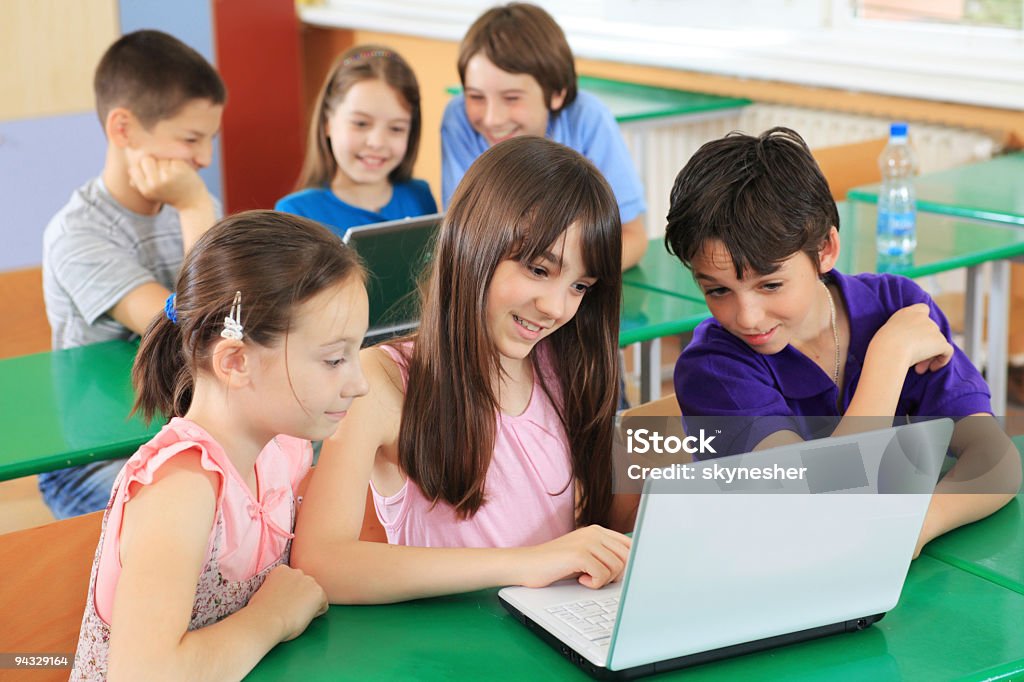 Schoolchildren having fun on laptops at  classroom.  Adult Student Stock Photo